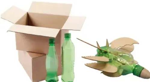 Caja de cartón abierta con botellas de plástico verde y un objeto elaborado a partir de botellas y cartón reciclado, ilustrando la transformación de residuos en objetos útiles.
