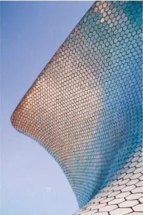Estructura arquitectónica curva con superficie teselada en tonos azules y verdes, semejante a escamas o panal de abeja.