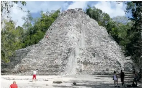 Pirámide alta y estrecha con escalinata larga, rodeada de árboles; es la pirámide de Cobá.