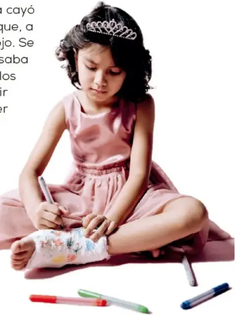 Niña sentada con vestido rosa, escribiendo o dibujando sobre un yeso en su pierna, con plumones de colores alrededor.