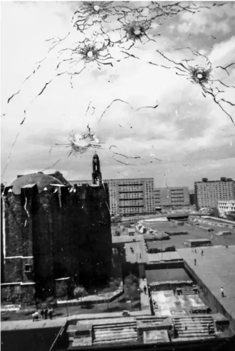 Fotografía en blanco y negro de un edificio con impactos de bala en la fachada y una plaza vacía al frente, que ilustra la represión del movimiento estudiantil de 1968.