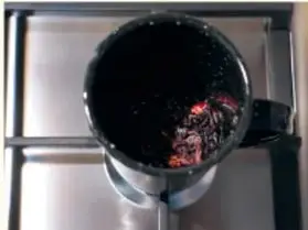 Vaso de precipitados sobre una parrilla eléctrica con líquido oscuro hirviendo.