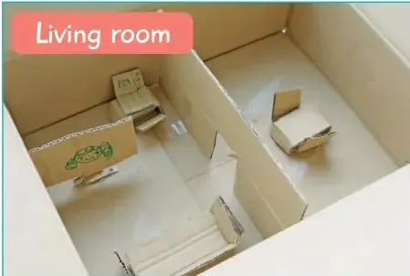 Fotografía de una maqueta de 'Living room' hecha con caja de cartón, con muebles de papel y bloques.