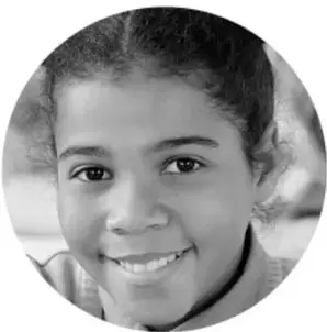 Fotografía en blanco y negro de una niña sonriente con cabello recogido.