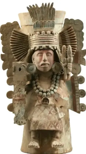 Escultura de la diosa Chicomecóatl: mujer madura con tocado alto, rostro pintado, collar de cuentas y mazorcas en las manos, con tocado que semeja una construcción o granero.