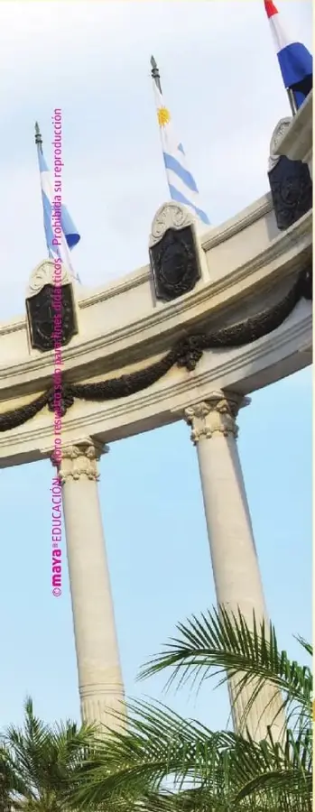 Fotografía de un monumento de Guayaquil con columnas, banderas y vegetación.