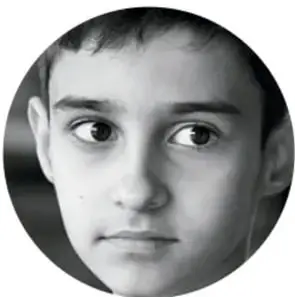 Fotografía en blanco y negro del rostro de un niño mirando de frente, con expresión pensativa.