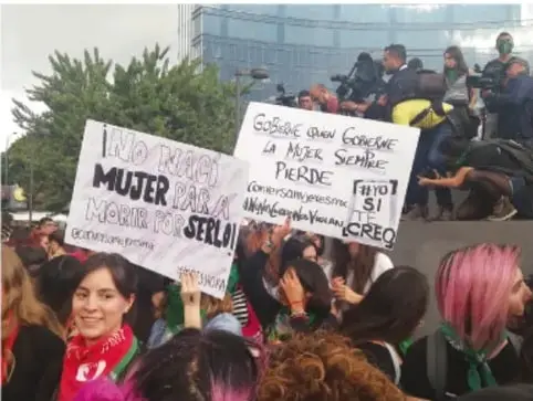 Fotografía de una marcha con personas sosteniendo carteles que dicen 'NO TRABAJO MUJER PARA MORIR POR SERLO' y 'GOBIERNE QUIEN GOBIERNE LA MUJER SIEMPRE PIERDE'.