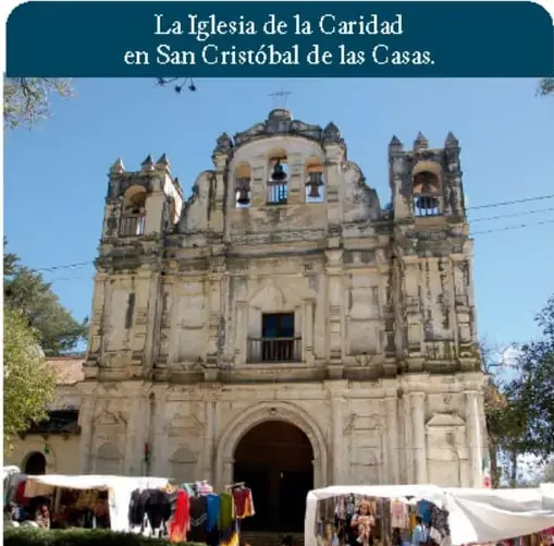 Fotografía de la fachada de la Iglesia de la Caridad en San Cristóbal de las Casas, con personas y puestos afuera.
