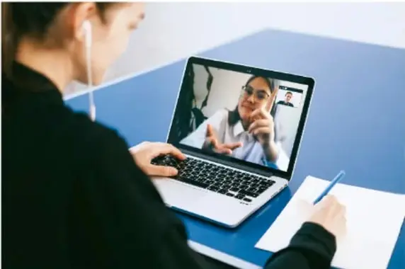 Persona usando una laptop para una videoconferencia con un profesional de salud, ejemplificando la comunicación remota actual.