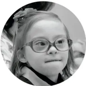 Fotografía en blanco y negro de una niña con lentes, sonriendo.