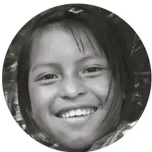 Fotografía en blanco y negro, en círculo, del rostro sonriente de una niña pequeña, alusiva al cuidado y la felicidad infantil.