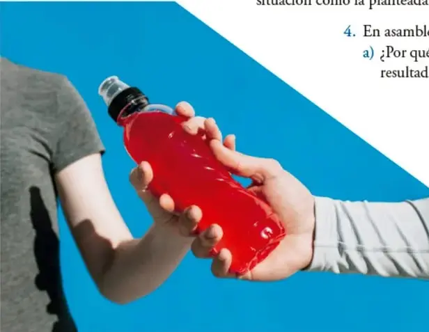 Persona entregando una botella con bebida roja, representando la bebida hidratante comercial.