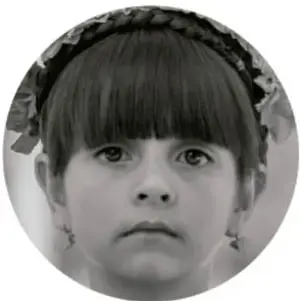 Fotografía en blanco y negro de una niña con flequillo y diadema, mirando de frente.
