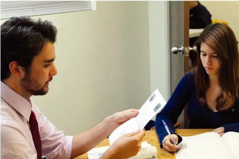 Fotografía de un hombre y una mujer analizando documentos y tomando notas en una mesa de trabajo, ilustrando el análisis de información en equipo.