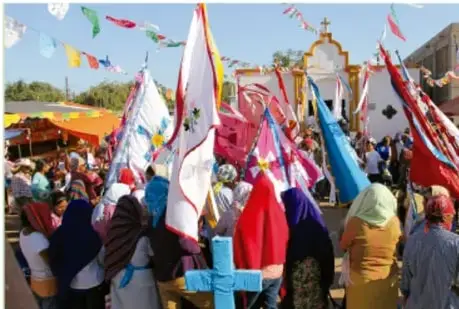 Fotografía de una fiesta popular con banderas y participantes, posiblemente fiesta patronal o celebración comunitaria.