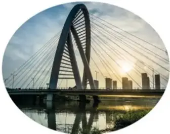 Fotografía de un puente atirantado con un arco, al atardecer, cuya forma recuerda a una cinta torcida.
