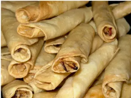 Fotografía de varios rollos de comida (burritos o tacos enrollados) apilados, como ejemplo de alimento preparado.
