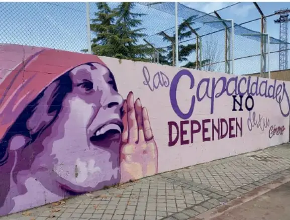 Mural urbano de gran formato en una cancha, con el rostro de una persona y la leyenda 'Las capacidades NO dependen de los demás', ejemplo de arte callejero con mensaje social.