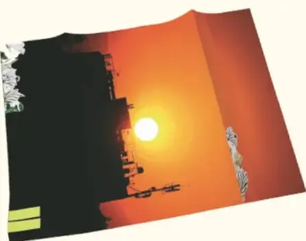 Fotografía atardecer naranja con la silueta de una casa o edificio y un poste, con un retazo verde abajo.