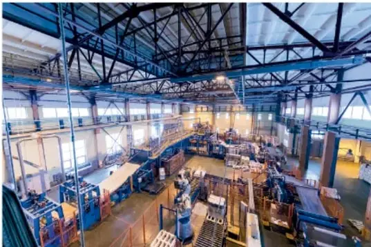 Interior de una planta industrial (manufacturera) con maquinaria, líneas de producción y estructura metálica de techo.