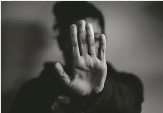 Fotografía en blanco y negro de una persona levantando la mano abierta en gesto de detención o rechazo, ilustrando la respuesta ante la violencia.