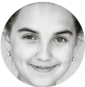 Fotografía en blanco y negro del rostro sonriente de una niña con aretes, mirando de frente.