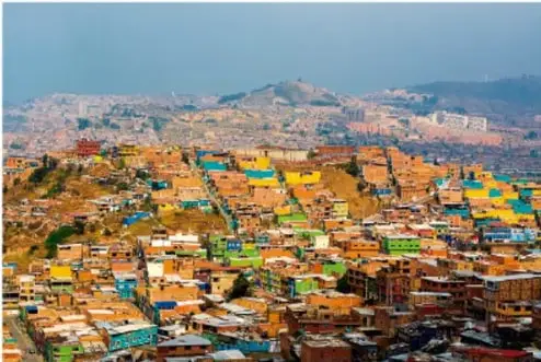 Vista panorámica de una ciudad con viviendas densamente agrupadas en una ladera, que ilustra condiciones de desigualdad urbana.