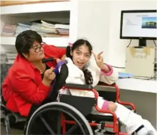 Persona en silla de ruedas acompañada de una estudiante, en un entorno escolar.