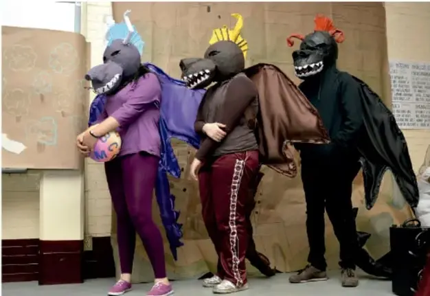 Fotografía de estudiantes con máscaras y capas (personajes de tertulia artística) durante la presentación de su proyecto en el aula.
