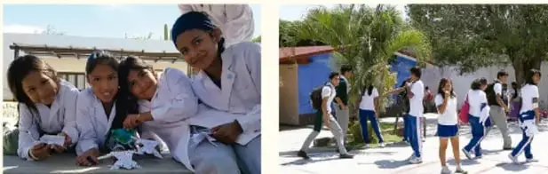 Fotografía de un grupo de estudiantes sonrientes, uno de ellos con uniforme escolar, sentados en el suelo.