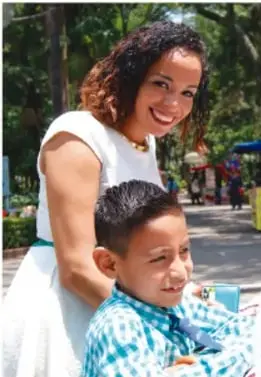 Mujer y niño sonriendo en un espacio público al aire libre, representando la convivencia respetuosa entre personas de distintos orígenes.