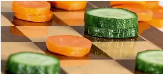 Fotografía a color de rodajas de zanahoria y pepino sobre una superficie a cuadros, que ilustra una alimentación saludable.