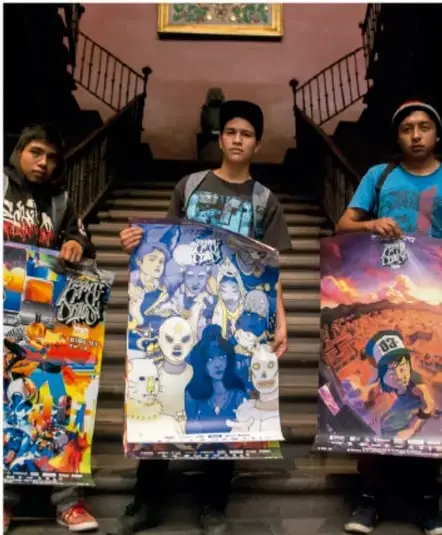 Tres jóvenes de pie en la escalera de un edificio sosteniendo carteles de arte con ilustraciones coloridas.