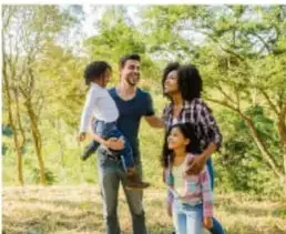 Fotografía de una familia (padre, madre y dos hijos) caminando juntos al aire libre en un entorno natural.