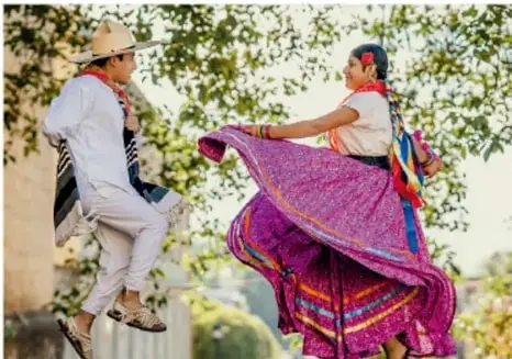 Pareja bailando con trajes tradicionales coloridos, representando la expresión cultural de la identidad.