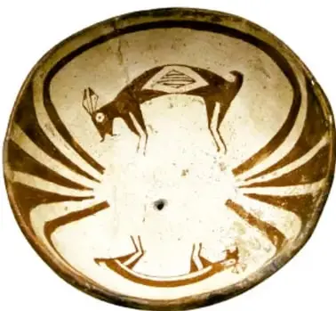 Vaso o cuenco de cerámica de fondo claro con decoración marrón de estilo mimbres: figura de animal (parecido a un ciervo o antílope) rodeada de motivos geométricos radiales.