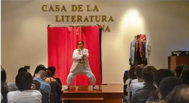 Fotografía de una representación escénica de La Llorona en la Casa de la Literatura: un actor sobre un escenario con cortina roja frente a un público.