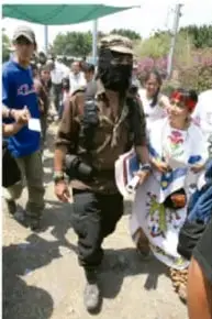 Personas caminando en una marcha, algunas con pasamontañas y vestimenta tradicional.
