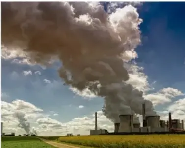 Fotografía de una central térmica o planta industrial emitiendo grandes columnas de humo a la atmósfera, representando la contaminación del aire por combustibles fósiles.