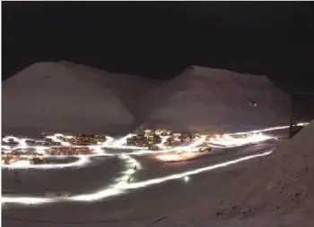 Paisaje polar nocturno con luces artificiales. El pie de imagen explica que durante los otros seis meses puede existir oscuridad o luz sin que el Sol sea visible.