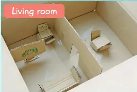 Fotografía de una maqueta de 'Living room' hecha con caja de cartón, con muebles de papel y bloques.