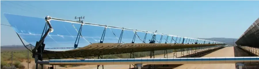 Fotografía de una planta de energía solar térmica con espejos cilíndrico-parabólicos alineados en un paisaje árido, que ilustra proyectos de infraestructura y desarrollo social.
