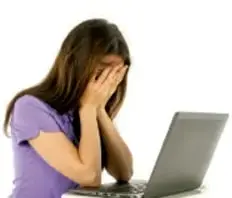Joven con la cabeza entre las manos frente a una laptop, mostrando angustia ante el acoso en línea (ciberbullying).