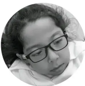 Fotografía circular en blanco y negro de una estudiante con lentes leyendo o escribiendo en su cuaderno.