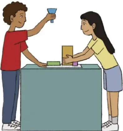 Dos estudiantes construyendo la maqueta sobre una mesa, uno añade material con un embudo.