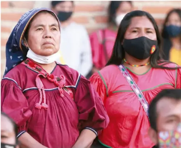 Fotografía de mujeres indígenas mexicanas con huipiles tradicionales rosas y rebozos, algunas con cubrebocas, en un acto público; ilustra la diversidad cultural y lingüística de México.