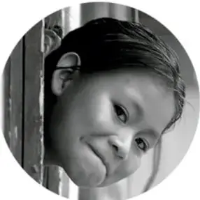 Fotografía en blanco y negro de una niña asomada, mirando hacia un lado.