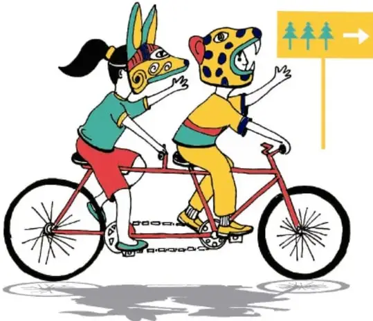 Dos niñas con máscaras de conejo y jaguar sobre una bicicleta-tándem roja, señalando un letrero amarillo con tres árboles y una flecha, que sugiere seguir una ruta (Rutila Vega Rubio, Tlaxcala).