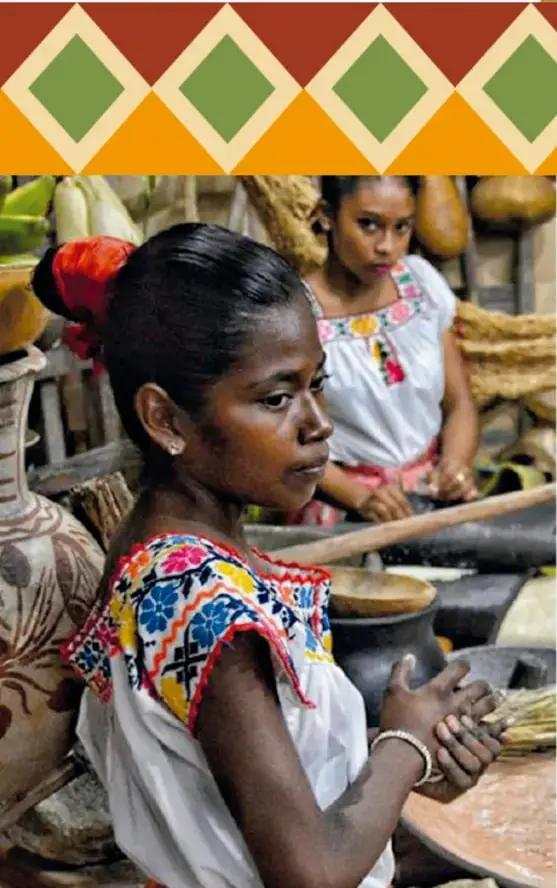 Fotografía de dos niñas afromexicanas con ropa tradicional bordada; la mayor moldea barro con sus manos en un taller de alfarería, rodeada de ollas y comales.